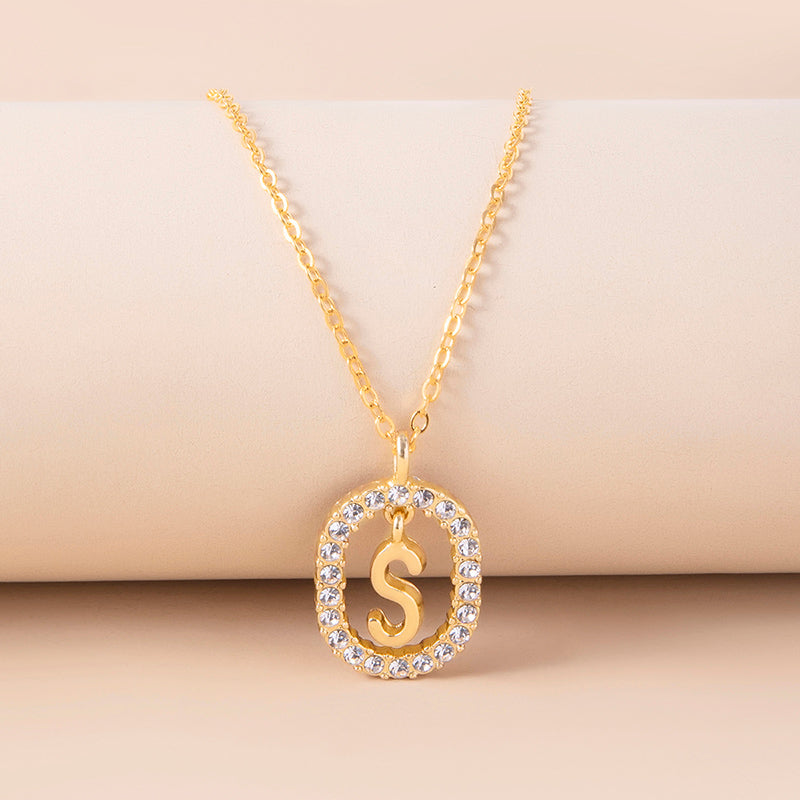 Gold necklace with a 'S' pendant on a beige background