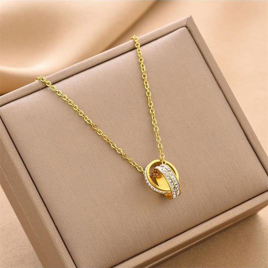 Gold necklace with a pendant on a beige jewelry box
