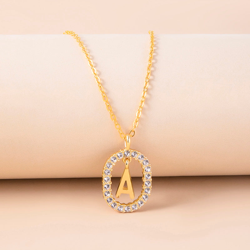 Gold necklace with a pendant featuring the letter 'A' on a beige background