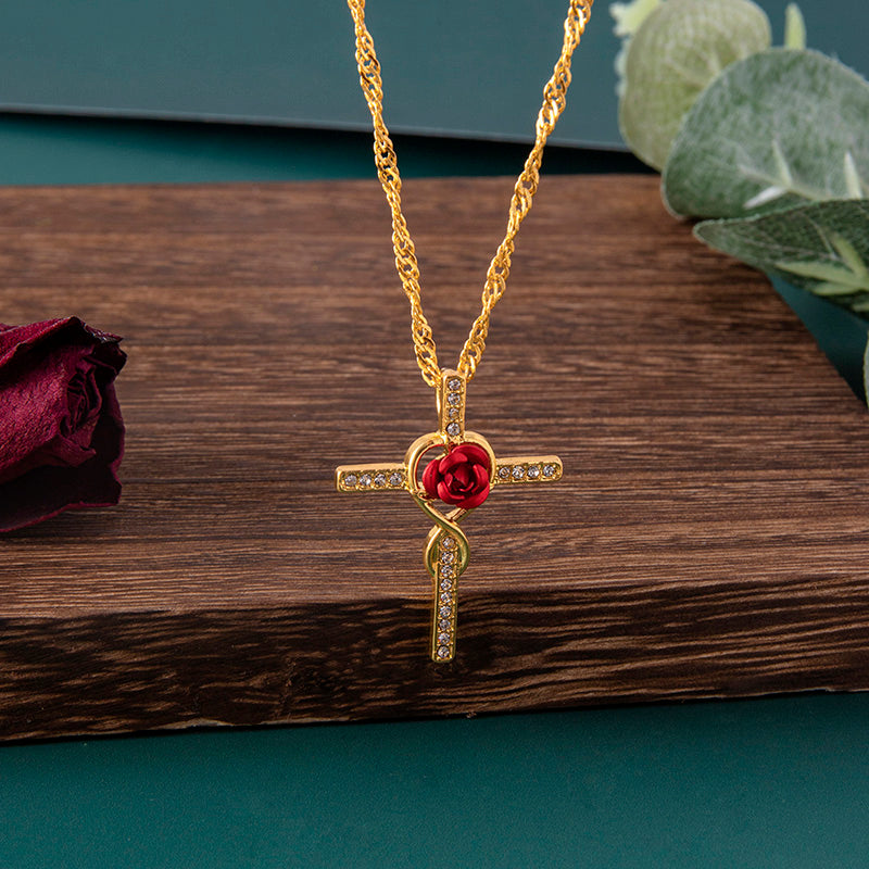 Gold necklace with a red rose pendant on a wooden surface