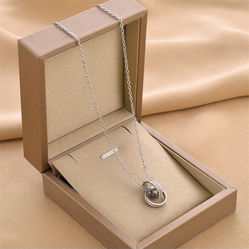 Silver necklace with a pendant in an open beige jewelry box on a beige fabric background
