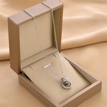 Silver necklace with a pendant in an open beige jewelry box on a beige fabric background